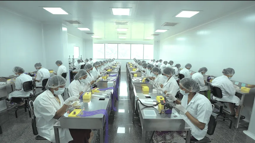 Operator memasang jarum pada benang bedah di meja kerja lantai produksi Dolphin Sutures