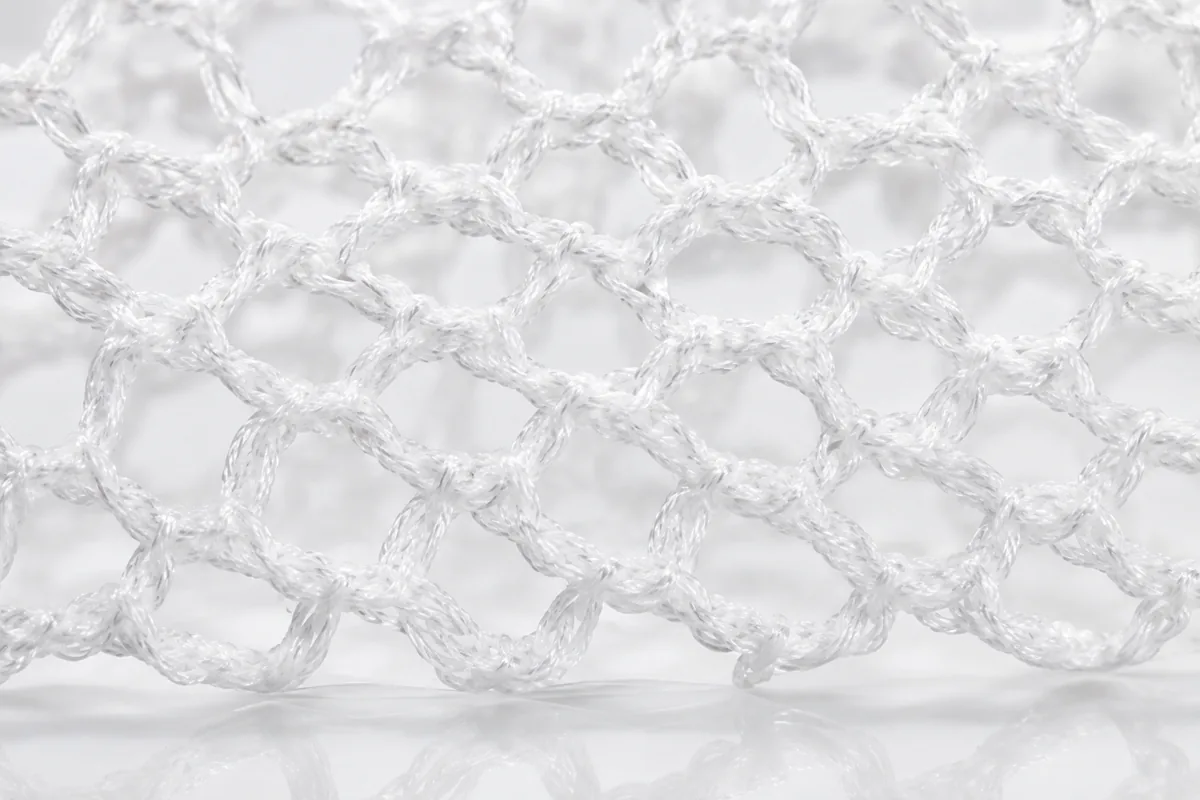 Extreme close-up of knitted surgical mesh, showing the individual monofilaments and the open pores between them.